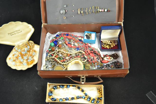 A vintage case containing sundry costume jewellery - necklaces, brooches etc