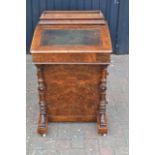 A Victorian figured walnut davenport, lifting lid with fitted interior, four drawers to side with