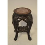 A Chinese carved hardwood pot stand with circular inset rouge marble, floral and leaf carving to