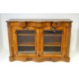 A Victorian figured walnut side cabinet, serpentine top, pair of glazed doors under, shaped base,