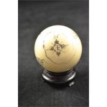 An ivory snooker ball with scrimshaw style carving depicting compass rose, merchantman and sea