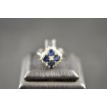 An 18ct white gold ring with four sapphires surrounded by diamonds in a floral setting, size L 1/2