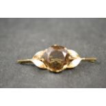 A 15k gold bar brooch set with smoky quartz flanked by gold foliate shoulders - brooch width 8cm