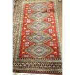 A Middle Eastern red ground rug, five diamonds to centre, surrounded by camels and rectangles,