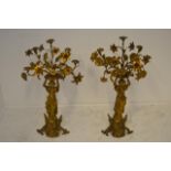 A pair of continental gilt brass candelabra formed as classical style maidens holding flowers aloft,