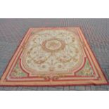 A French style tapestry carpet with centre floral roundel and floral decoration to corners -