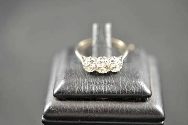 An 18ct gold and platinum ring set with three diamonds, size O 1/2, centre diamond approximately .