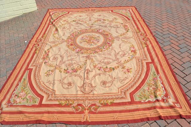 A French style tapestry carpet with centre floral roundel and floral decoration to corners -