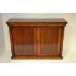 An early 19th Century mahogany side cabinet enclosed by a pair of panelled doors, columns to side