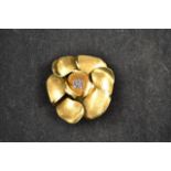 An 18ct gold brooch of stylised floral form, the centre set with seven sapphires - diam 4.5cm,