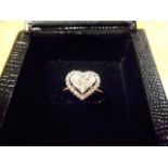 An 18ct white gold ring with three diamonds to centre forming a heart, surrounded by twenty two