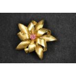 An 18ct gold brooch of stylised floral form, the centre set with seven rubies - W5.3cm, approx gross