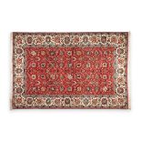 A PERSIAN WOOL TABRIZ CARPET, MODERN, with red field of stylized blossoming foliage, within a