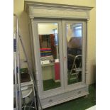 A painted armoire with two bevelled mirror doors with long drawer to base.