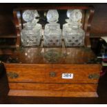 A late Victorian oak Tantalus with three glass decanters, card and cigar box to front