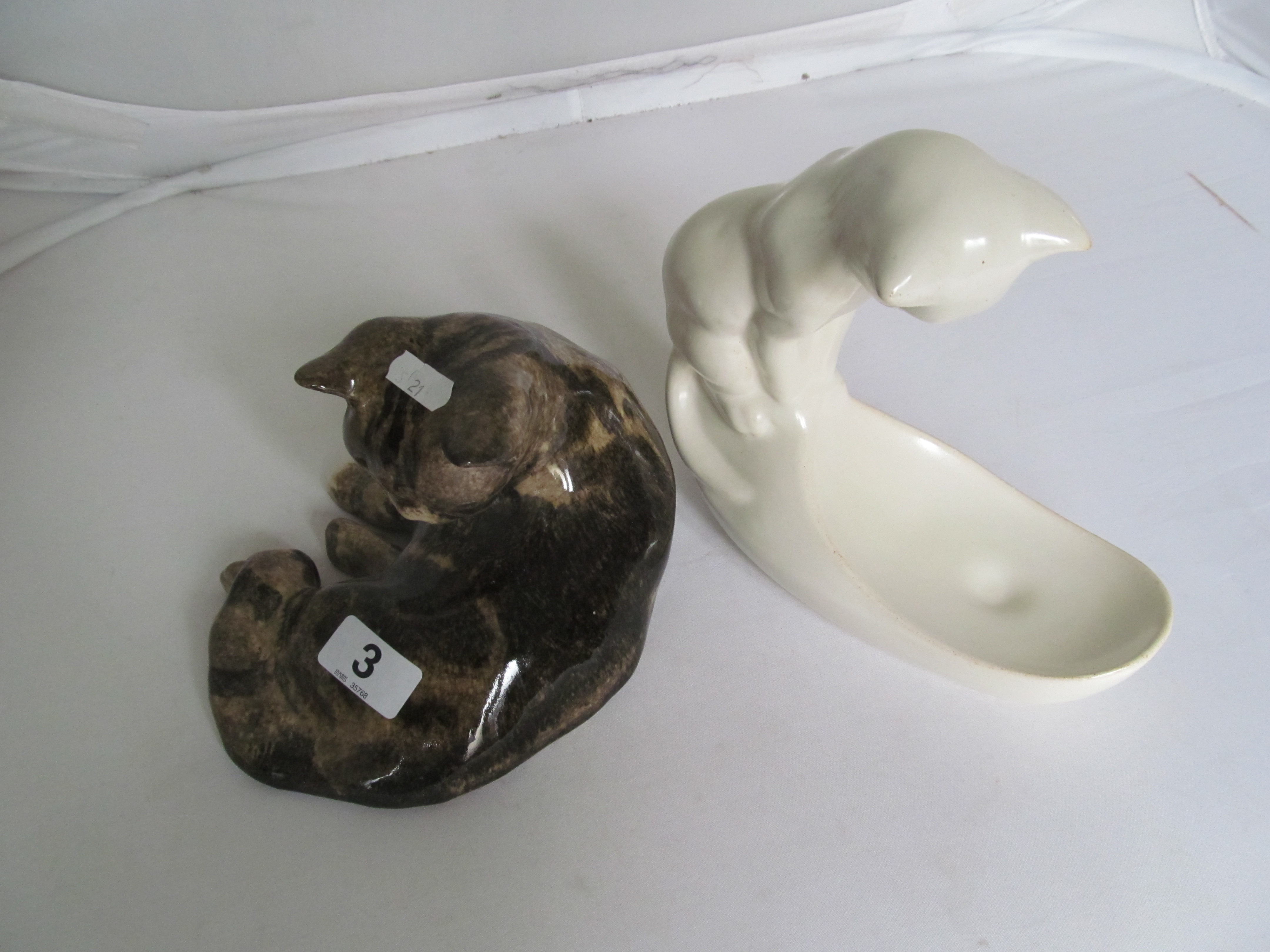 A cream pottery cat dish and a Winstanley pottery sleeping cat.