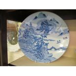 An oriental design blue and white plate with temple and houses on hill