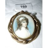 An early 19th century oval portrait miniature in ornate pinchbeck brooch mount