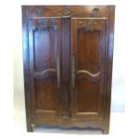 An 18th Century French Oak Armoire with two carved panelled doors and with brass escutcheons above