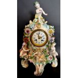 A Late 19th Early 20th Century German Porcelain Table Clock with putti cresting and with foliate