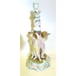 A German Porcelain Table Centre in the form of three putti upon a shaped scroll base,