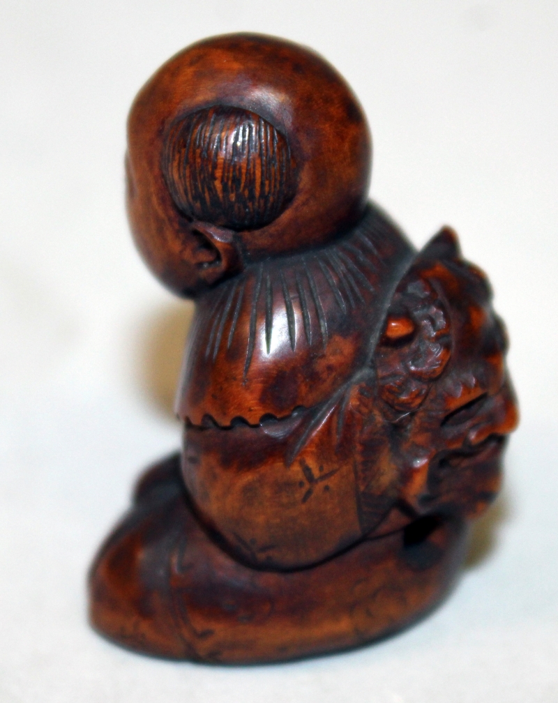 A JAPANESE MEIJI PERIOD WOOD NETSUKE OF A SEATED BOY, with protruding tongue, and holding an oni - Image 4 of 5