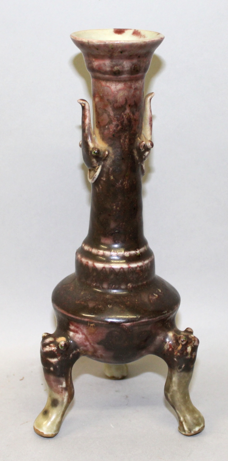 AN UNUSUAL CHINESE PORCELAIN TRIPOD CANDLESTICK, applied with a purple-red glaze and with inverted