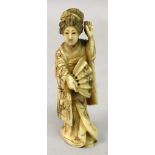 A JAPANESE MEIJI PERIOD IVORY OKIMONO OF A GEISHA, standing in flowing robes and holding a fan,