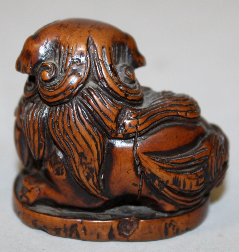 A JAPANESE CARVED WOOD NETSUKE OF A BUDDHISTIC LION, it's head resting on a pierced ribboned ball, - Image 3 of 5