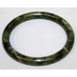 A CHINESE SPINACH GREEN JADE-LIKE BANGLE, the predominantly dark green stone with black and paler