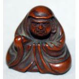 A SIGNED JAPANESE MEIJI PERIOD WOOD NETSUKE OF DARUMA, seated in flowing robes and holding a fly