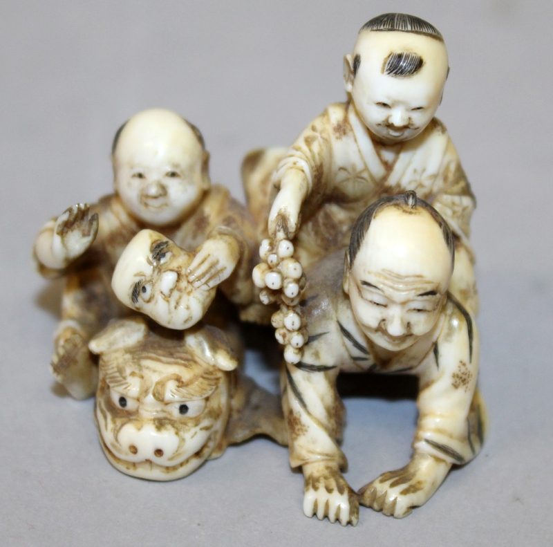 A GOOD QUALITY JAPANESE MEIJI PERIOD IVORY OKIMONO OF A MAN & TWO BOYS, one child holding grapes and