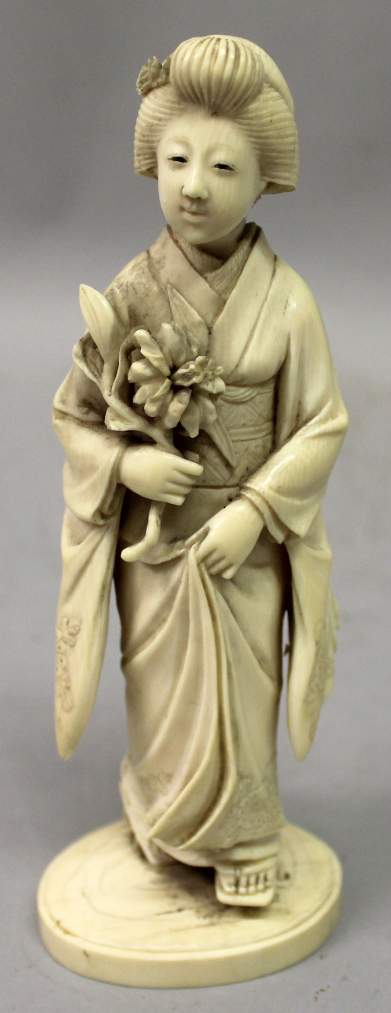 A GOOD QUALITY SIGNED JAPANESE MEIJI PERIOD OKIMONO OF A GEISHA, standing in flowing robes, her feet