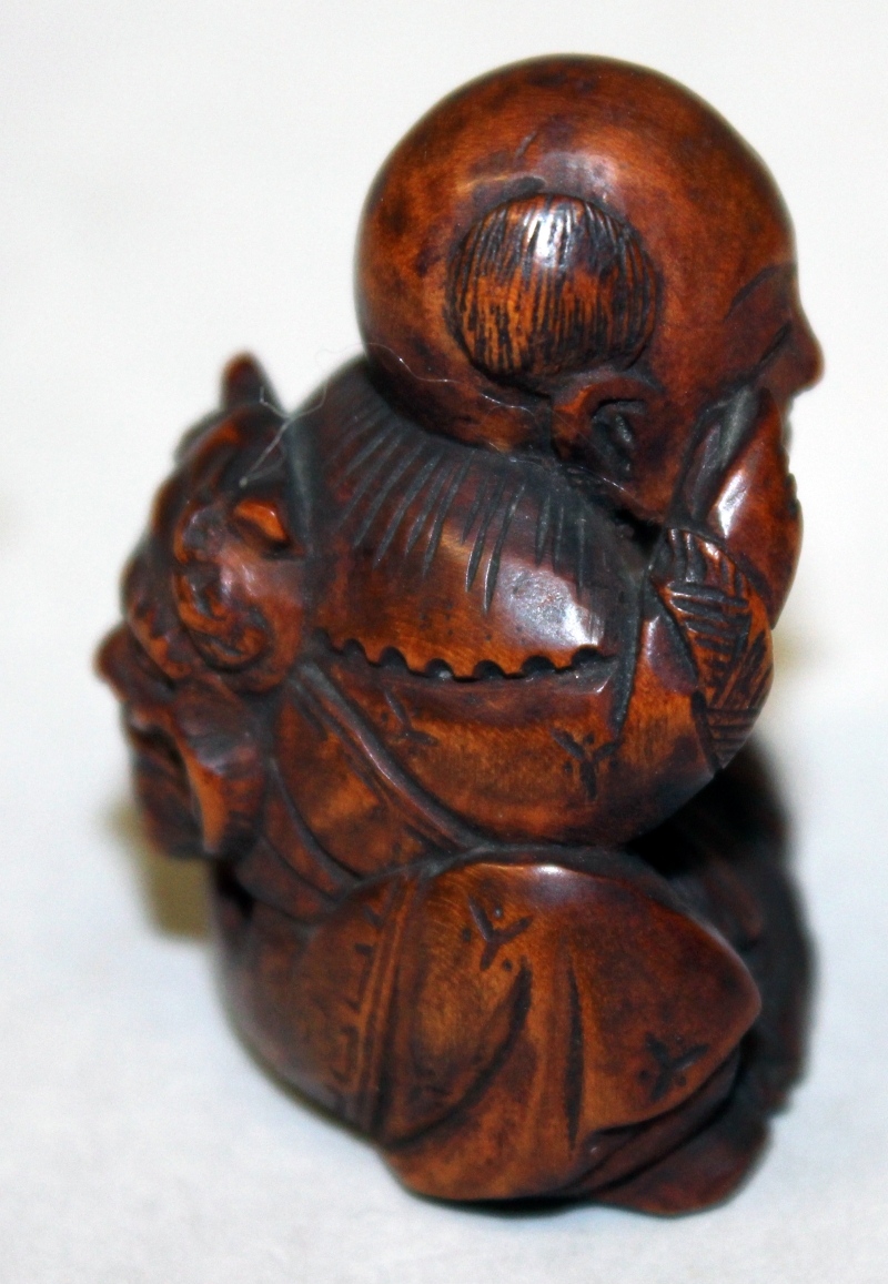 A JAPANESE MEIJI PERIOD WOOD NETSUKE OF A SEATED BOY, with protruding tongue, and holding an oni - Image 2 of 5