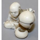 A SIGNED JAPANESE MEIJI PERIOD IVORY NETSUKE OF A SEATED MAN, holding aloft a temple bell, the