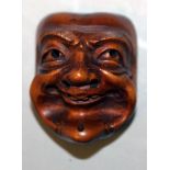 A JAPANESE MEIJI PERIOD WOOD NOH MASK NETSUKE, of a man with smiling features and pronounced