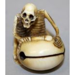 A SIGNED JAPANESE MEIJI PERIOD IVORY NETSUKE OF A SKELETON, kneeling before a temple bell, the
