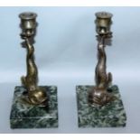 A PAIR OF BRONZE DOLPHIN CANDLESTICKS on marble bases. 7ins high.