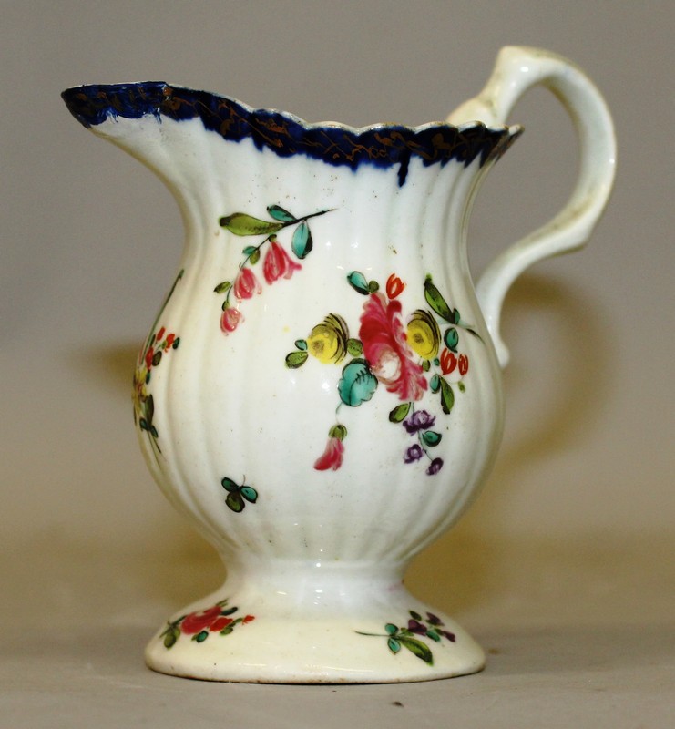 AN 18TH CENTURY LIVERPOOL PEDESTAL CREAM JUG with biting snake handle painted with flowers under a