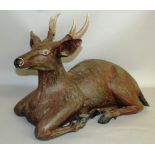 A LARGE "BLACK FOREST" CARVED AND PAINTED WOOD MODEL OF A RECUMBENT DEER.  2ft 4ins long.