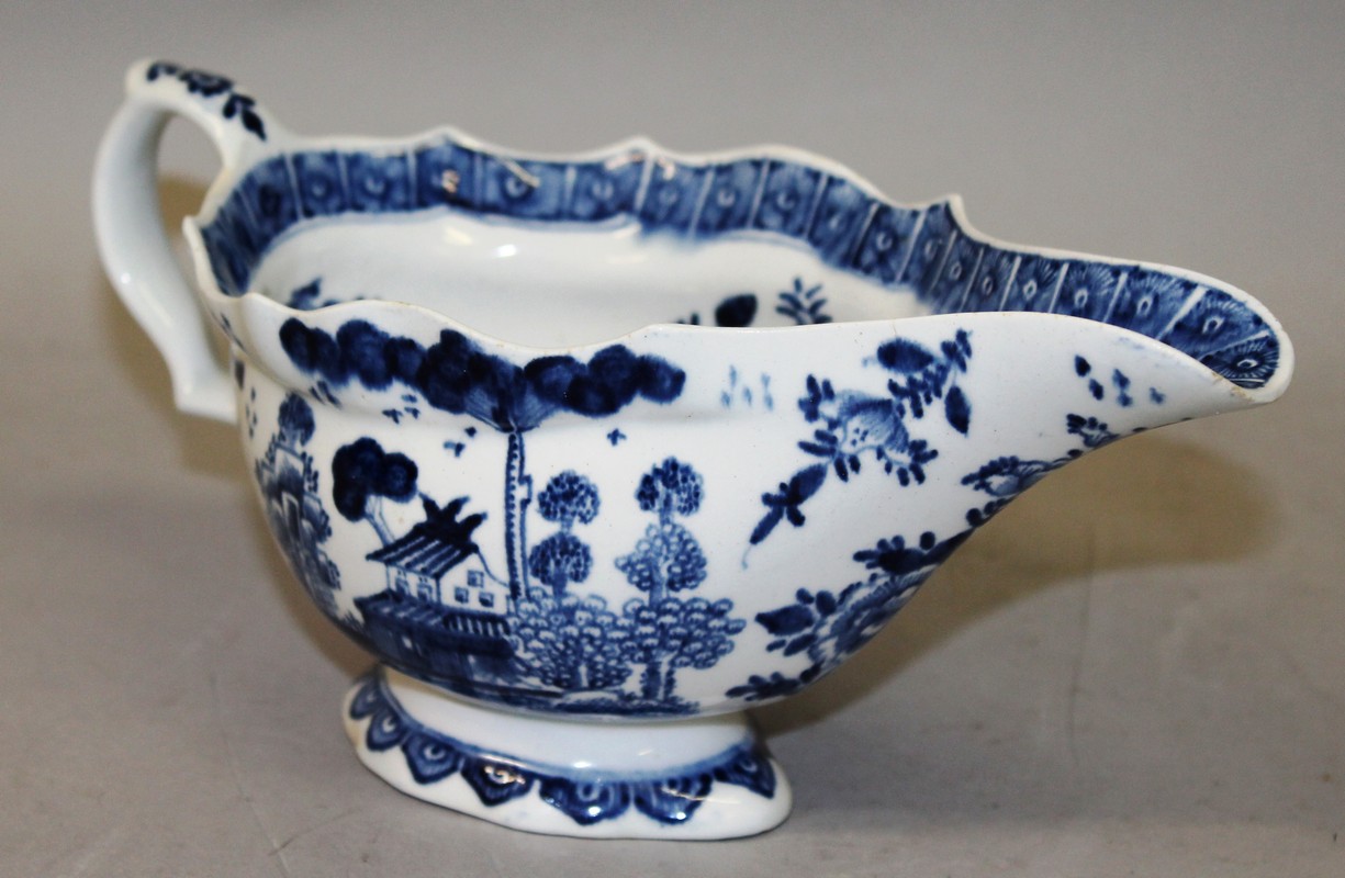 AN 18TH CENTURY BOW SAUCEBOAT painted in blue underglaze with a house in a Chinese landscape.