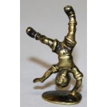 A YELLOW METAL NOVELTY SEAL, cast as a boy balancing on one hand, with blank shaped oval base. 5.