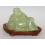 A 20TH CENTURY CHINESE GREEN BOWENITE CARVING OF BUDAI, together with a fitted wood stand, the deity