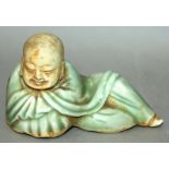 A CHINESE CELADON GLAZED FIGURE OF BUDAI, reclining in a closely drawn robe, his head and the base