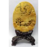A CHINESE CARVED SOAPSTONE OVAL PLAQUE ON STAND, one surface carved in high relief with a river