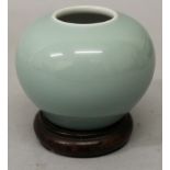 A CHINESE CELADON GLAZED WATER POT, together with a fitted wood stand, the sides applied with an