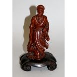 AN EARLY 20TH CENTURY CHINESE CARVED WOOD FIGURE OF AN IMMORTAL, together with a fixed wood stand,