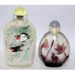 TWO 20TH CENTURY CHINESE GLASS SNUFF BOTTLES & STOPPERS, one interior painted, the second of red