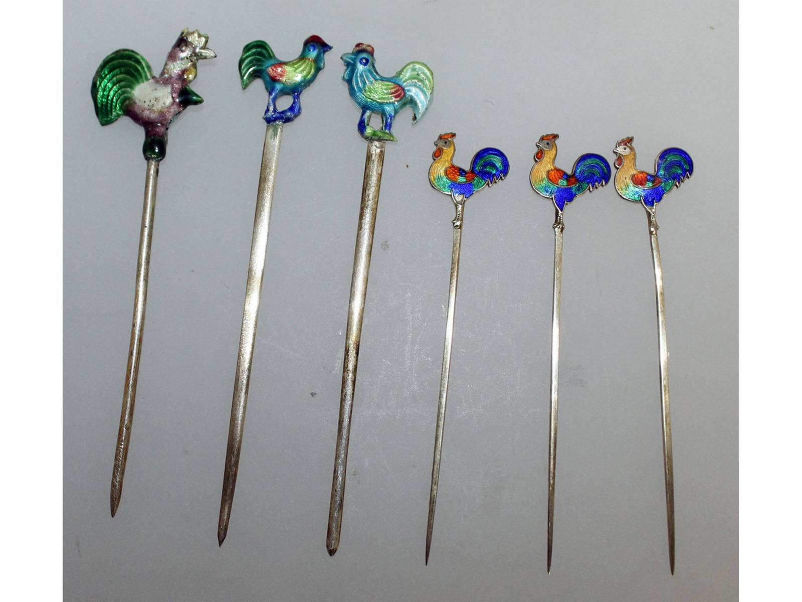 A set of six sterling silver pickle sticks with enamel cockerel handles.
