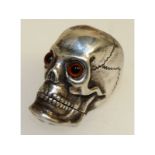 A silver skull vesta case with glass eyes.